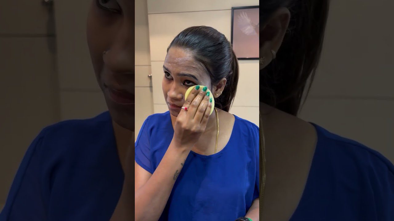 Moteris su surištais plaukais valosi makiažą kempine prie veidrodžio