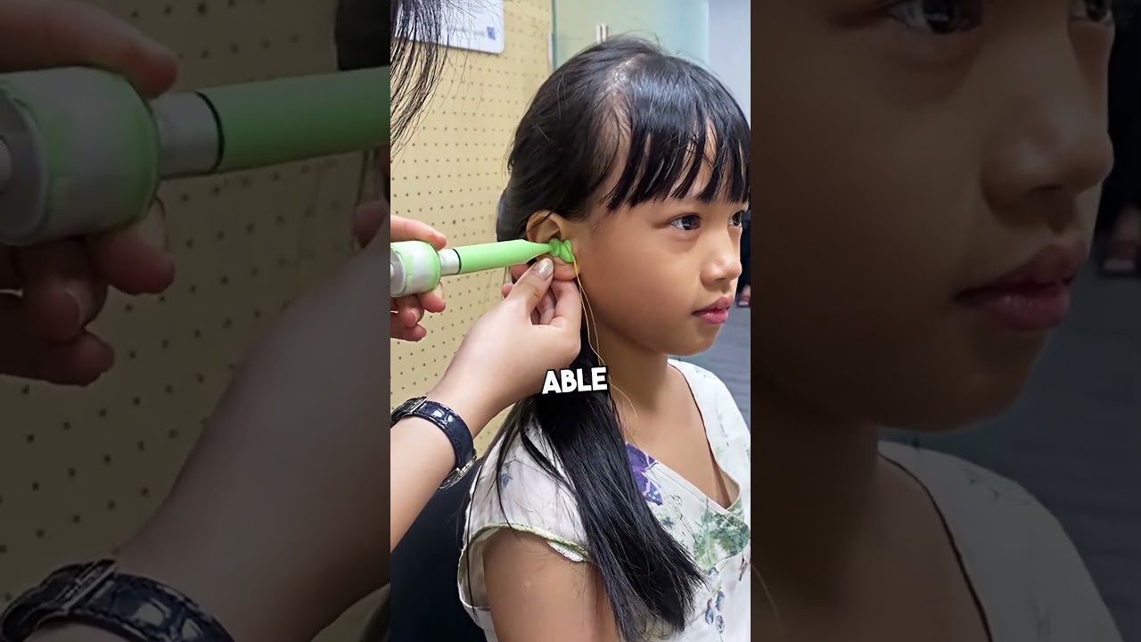 Vaikas sėdi, jai įstatoma žalia ausų valymo priemonė ir prilaikomas ausų volelė.