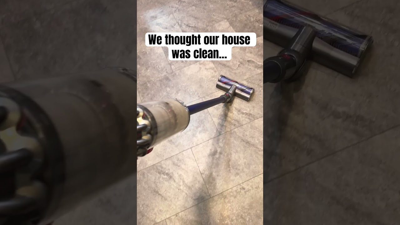 Rankinis belaidis dulkių siurblys valantis plytelių grindis su užrašu „We thought our house was clean“ (mąstėme, kad namai švarūs)
