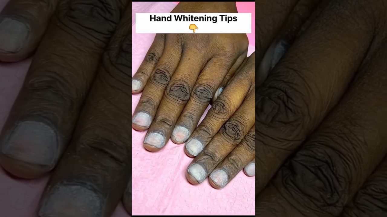 Tamsios odos rankos su baltais nagų gydymo likučiais ant rodomųjų ir nykščių