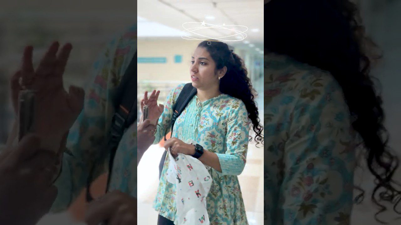 Jauna moteris su kuprine ir maišeliu, nustebusi kalbasi koridoriuje.