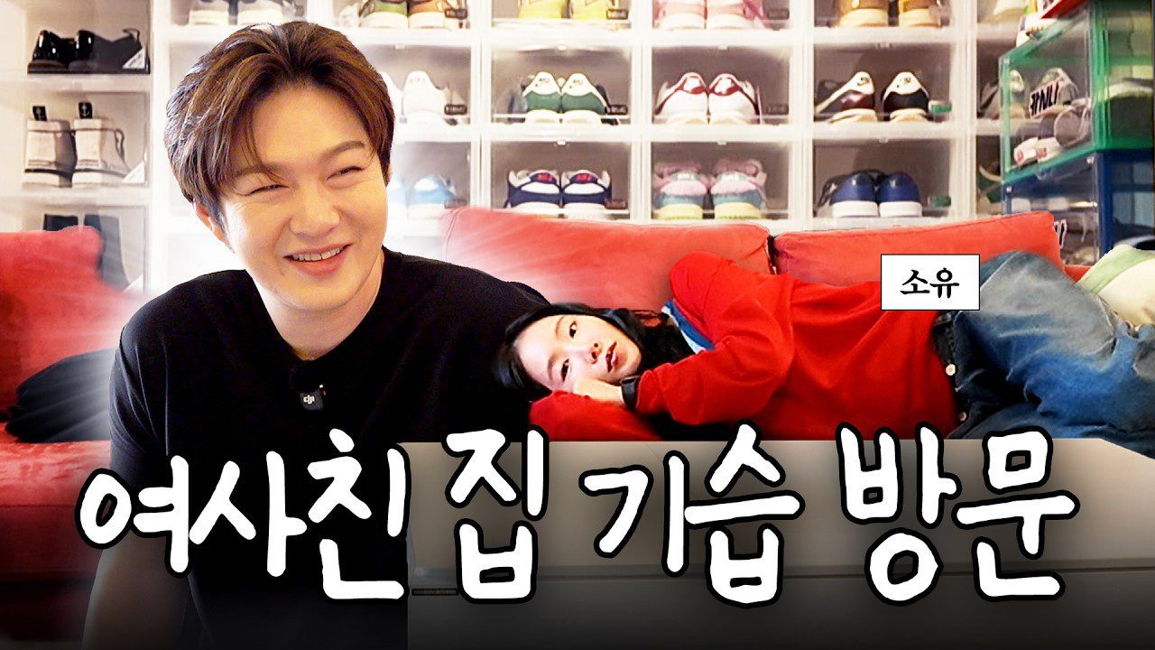 Vyriškis šypsosi prie raudonos sofos, moteris guli šalia ir žiūri į kamerą, tekstas korėjietiškai: „girlfriend visit“