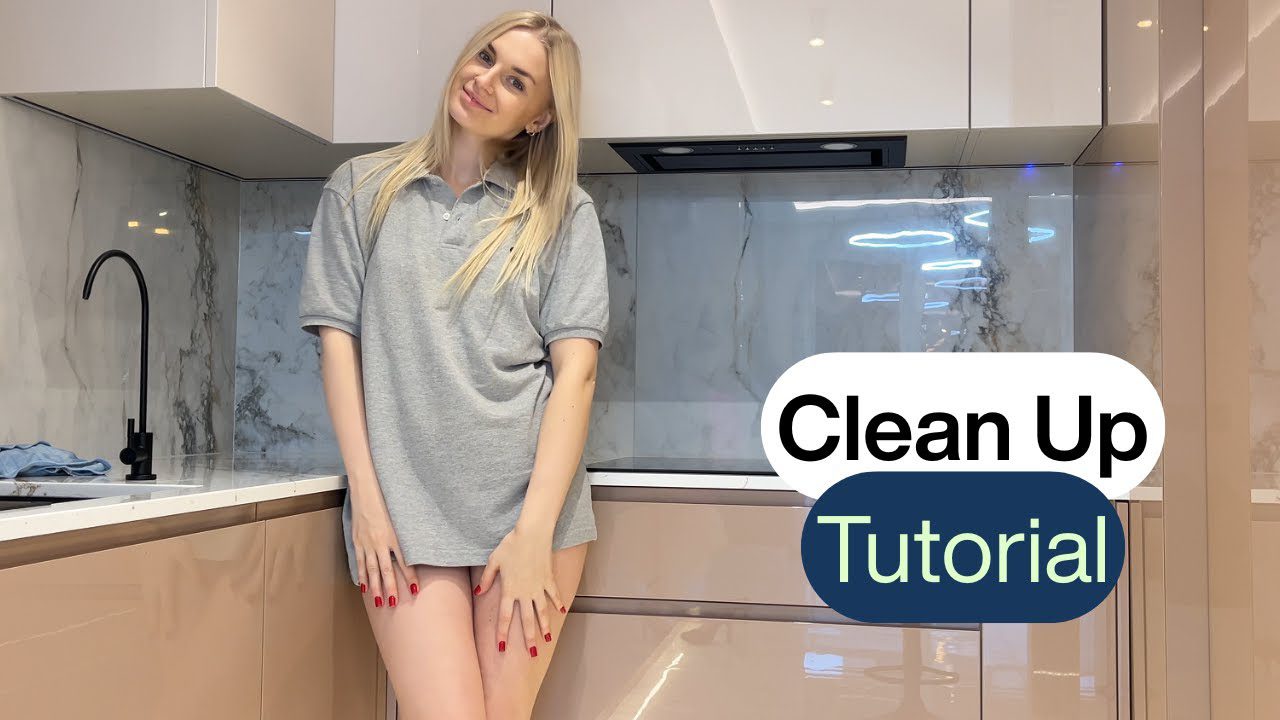 Blondinė moteris vilki pilką palaidinę stovi modernioje virtuvėje prie kriauklės, tekstas „Clean Up Tutorial“