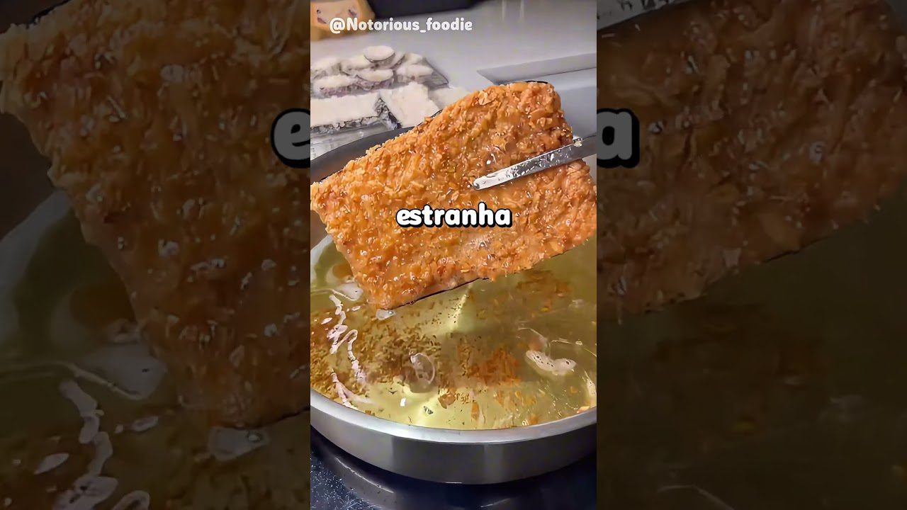 Traškiai keptas, auksinės rudos plokštelės formos maistas virš karšto aliejaus, žirklės laikosi už kampo