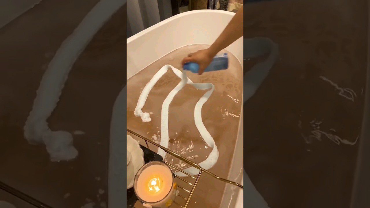 Rankomis į vonią pilamas putų skalbiklis, ant vandens susidaro balti vingiai