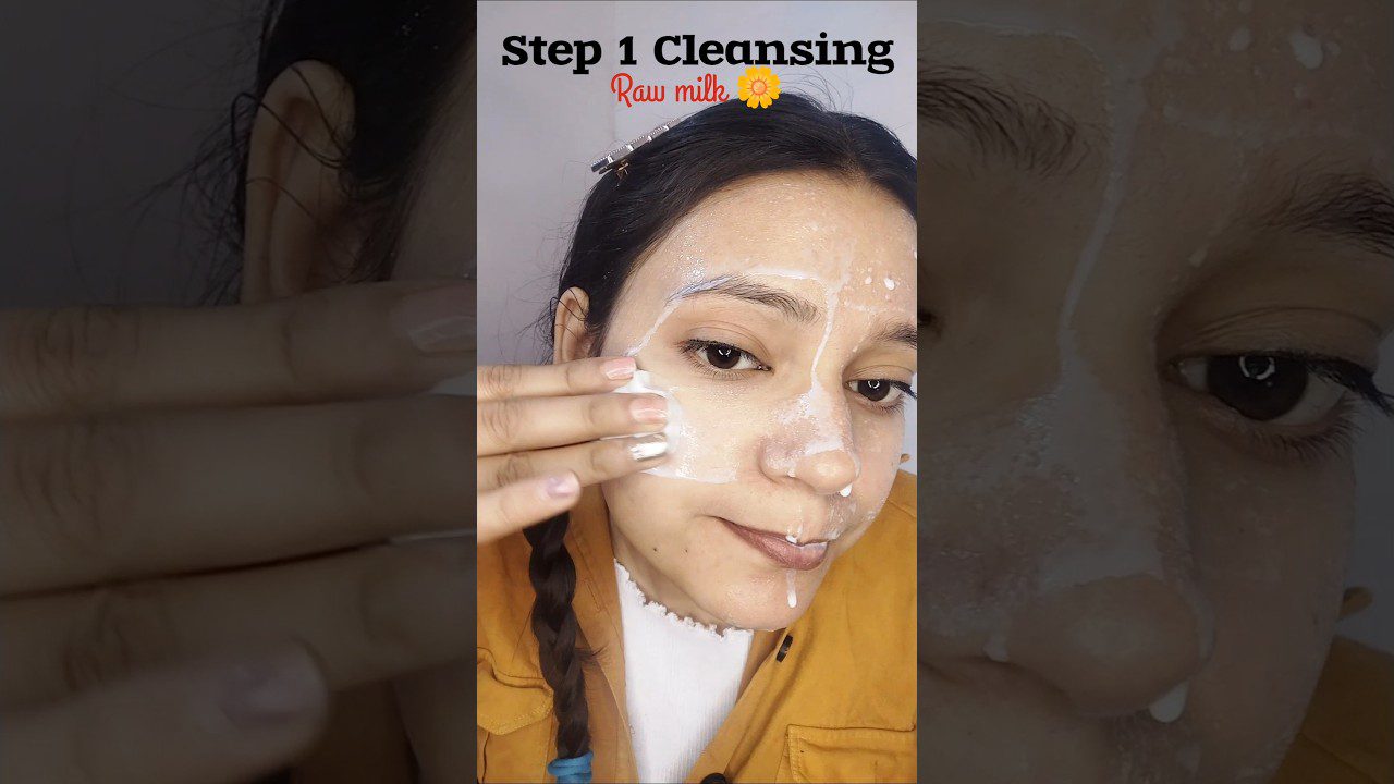 Moteris tepasi valantį pieno pagrindo veido prausiklį, matomas užrašas „Step 1 Cleansing“ ir „Raw milk“