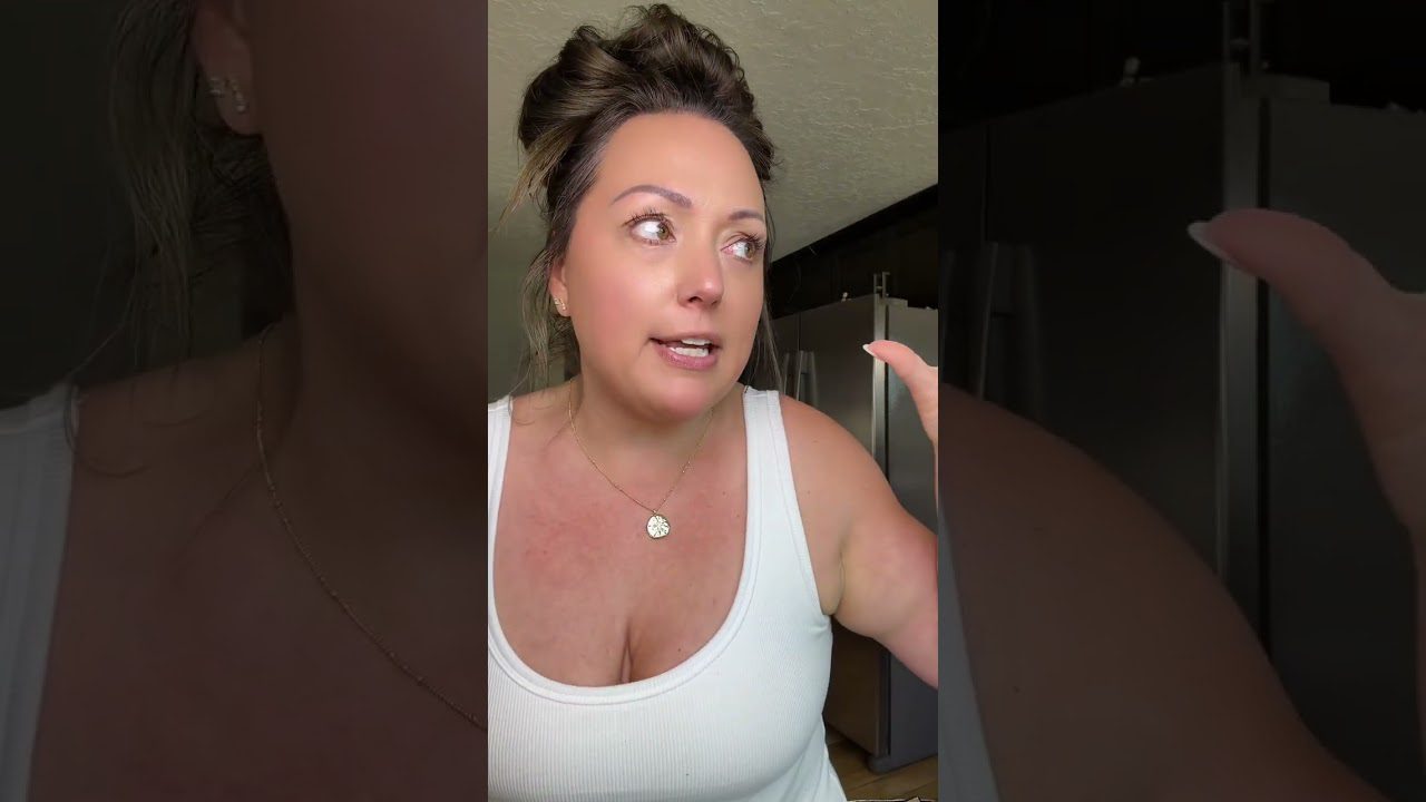 Moteris su sukirpta šukuosena ir baltu tankiniu topu kalba virtuvėje, mostuodama ranka