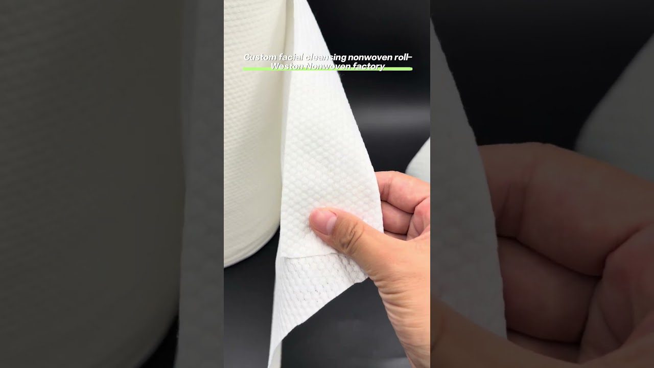 Rankais laikomas baltas vienašluostis neaudžtas popierius su tekstūra ir užrašu.