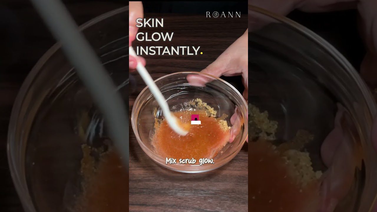 Rankos maišo oranžinį šveitiklį stiklinėje dubenyje, viršuje užrašas „Skin glow instantly“