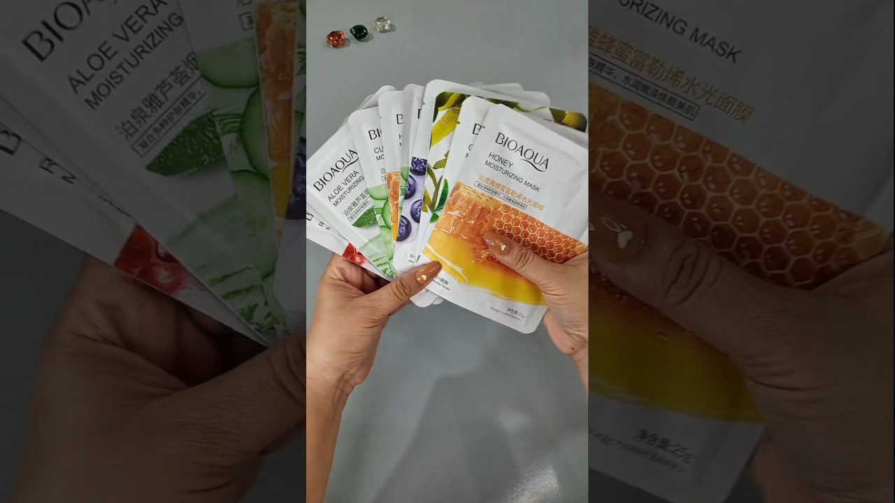 Rankose laikomi keli BIOAQUA veido kaukių paketėliai: medaus, alavijo ir uogų variantai.