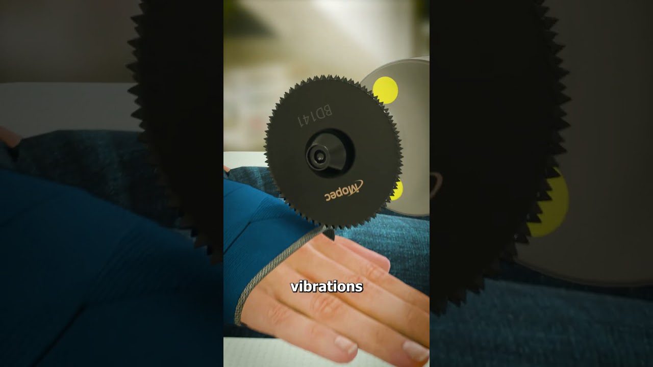 Rankos delnas po besisukančiu juodu dantytu disku su užrašu "vibrations" (vibracijos).