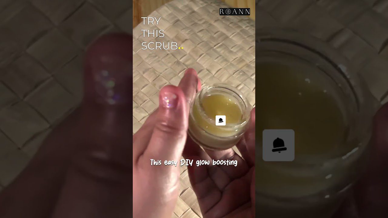 Rankoje laikomas mažas stiklinis indelis su geltonu DIY veido šveitikliu ir tekstu TRY THIS SCRUB.