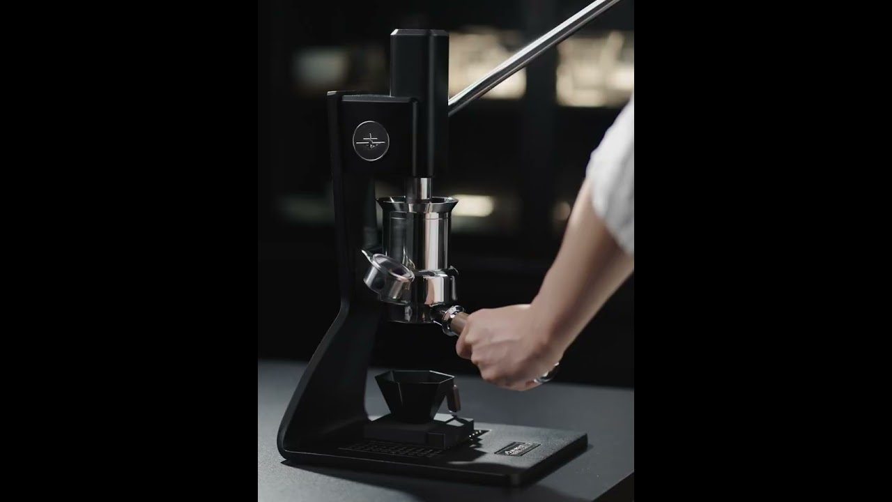 Rankinė kavamalė su portafiltru, barista įstatantis laikiklį po presu.
