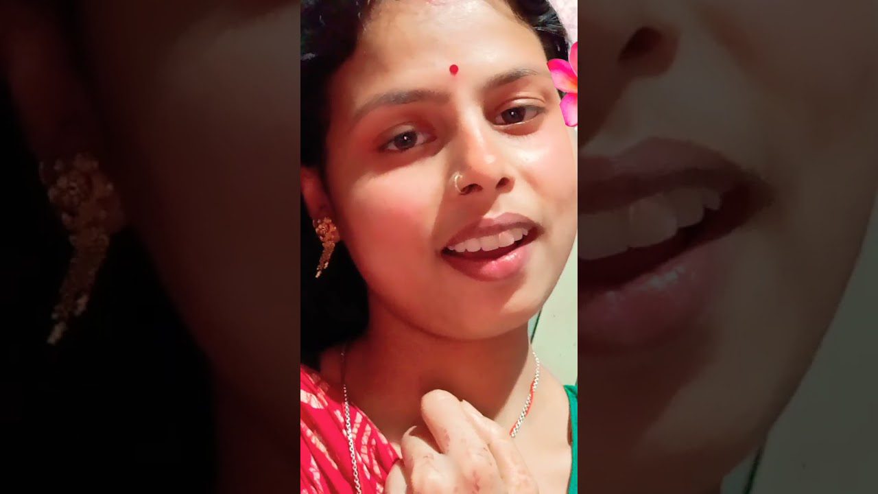 Jauna moteris su raudonu bindi ant kaktos, auskarais ir gėlės filtro efektu šone.