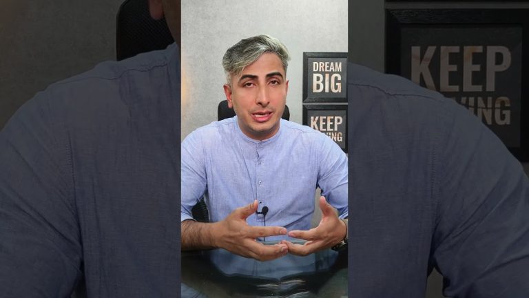 Vyriškis su pilkais plaukais kalba priešais mikrofoną, fone užrašai „Dream Big“ ir „Keep Going“