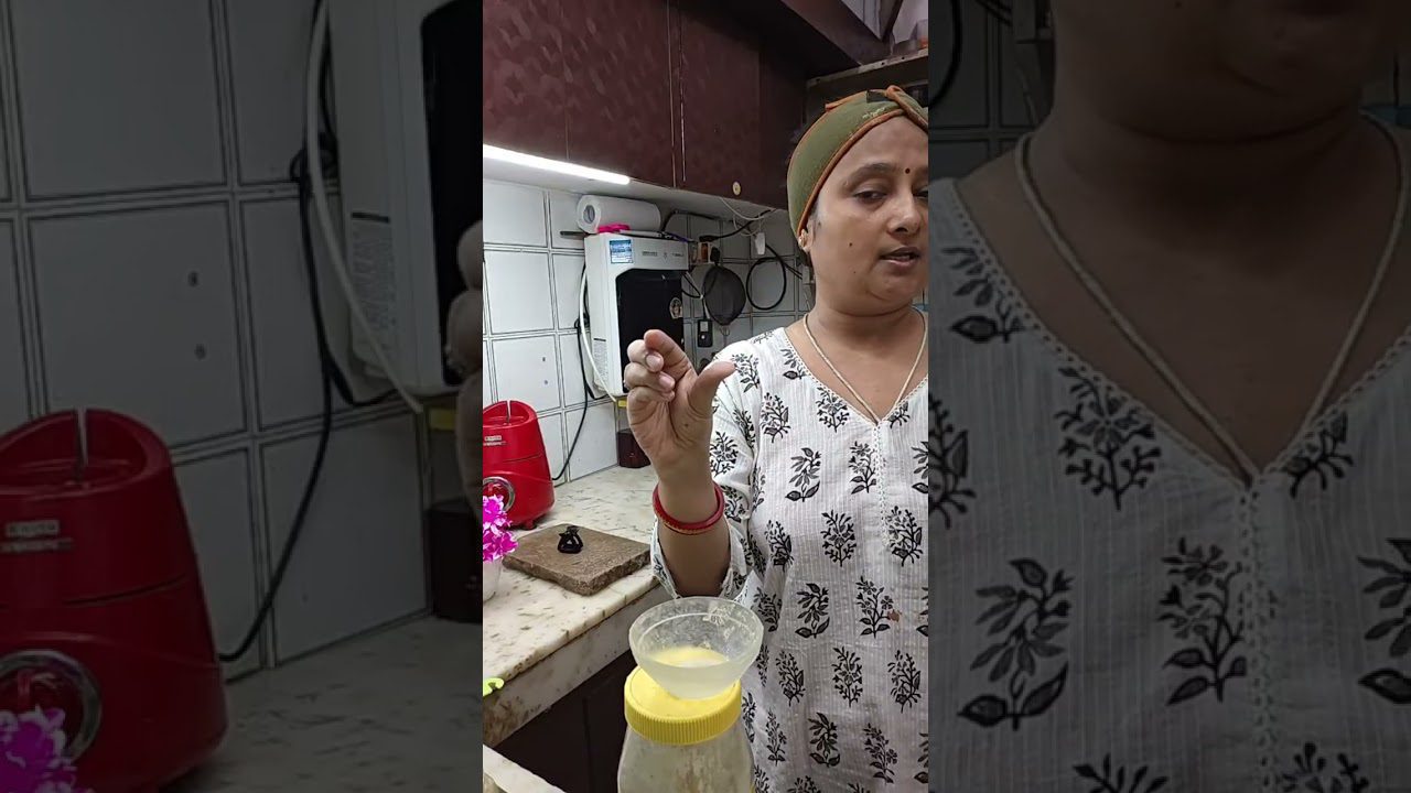 Moterys virtuvėje demonstruoja mažą lašą skysto ingredientų virš stiklinės su dangteliu.