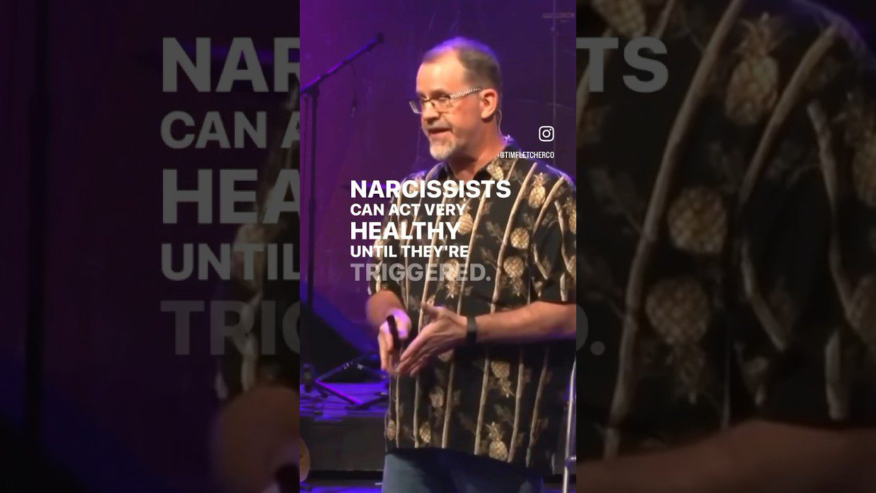 Vyras scenoje kalba prie mikrofono, fone užrašas „Narcissists can act very healthy“