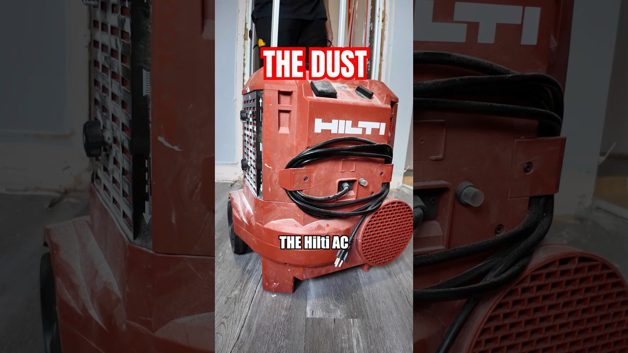 Raudonas Hilti dulkių siurblys su suvyniotu kabeliu ant statybų grindų