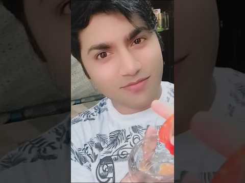 Jaunas vyras baltame marškinėlyje šypsosi ir laiko plastikinius buteliukus su raudonu dangteliu.